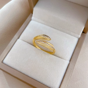 Adjustable golden feather open ring with sparkling cubic zirconia on a jewelry box