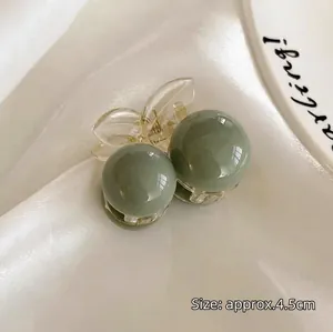 Detailed view of a green ball hair claw clip on silk fabric with 4.5cm size scale