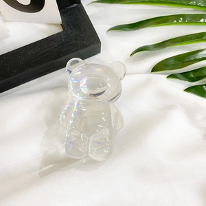 Macro shot of laser iridescent bear phone socket on white fabric with palm leaves