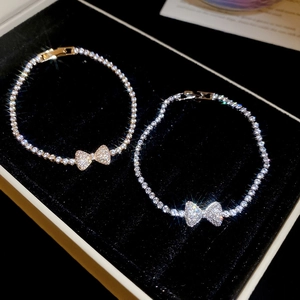 Macro shot of gold and silver bow knot tennis bracelets with zircons on black velvet