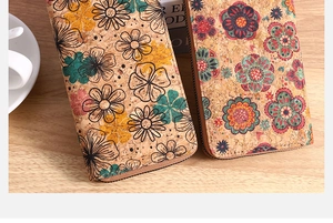 Detail view of natural cork zip wallets with vintage floral patterns on a wooden desk