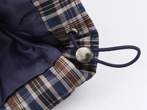 Detailed macro view of plaid jacket featuring blue drawstring and metal spring toggle