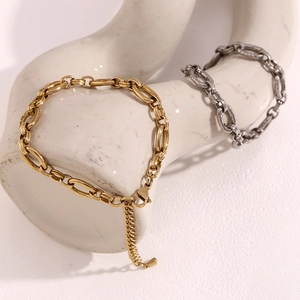 Close-up of gold and silver stainless steel oval link chain bracelets on ceramic decor