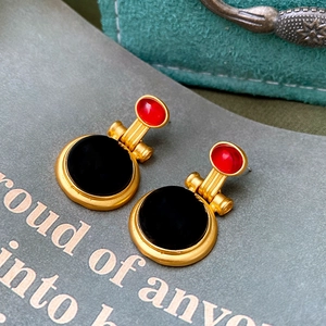 Close-up of vintage geometric earrings with red and black crystals in gold finish