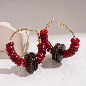 Detailed shot of ethnic hoop earrings with red and brown coconut shell beads on a white block