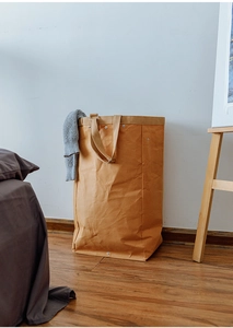Detail of large washable kraft paper storage basket with handles on wooden floor