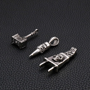 Close-up of retro Thor's hammer and skull steel pendants on black leather surface