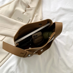 Top view of large brown leather tote bag interior showing capacity for books and phone