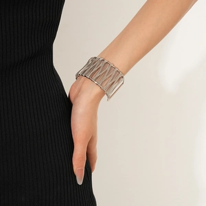 Vue détaillée d'un bracelet manchette argenté ajouré et entrelacé porté au poignet
