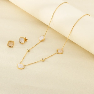Close-up of golden shell jewelry set with necklace and earrings on neutral backdrop