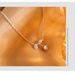 Macro shot of silver rose pendant with pavé crystals on golden silk fabric background