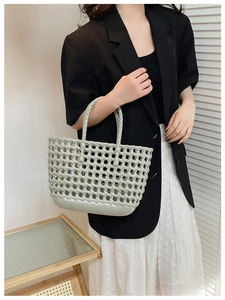 Hollow woven jelly bag in grey-green held by a model for daily holiday beach use