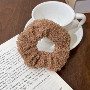 Brown teddy fleece scrunchie for hair styling on a cozy desk with a book and coffee