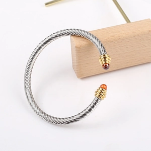 Twisted cable stainless steel cuff bracelet with gold caps and orange gemstones