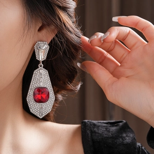 Macro view of silver geometric earrings with red gemstone and pavé rhinestones