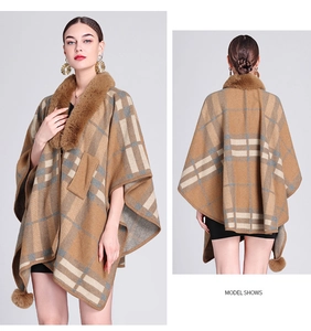 Close-up of camel plaid knit poncho with faux rabbit fur collar and pom-pom trim detail