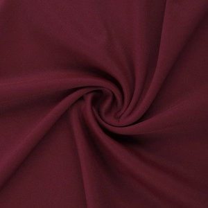 Close-up of wine red knitted fabric texture with elegant drapes and soft folds