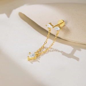 Détail d'une boucle d'oreille en argent S925 doré avec nœud diamanté et pampille en losange