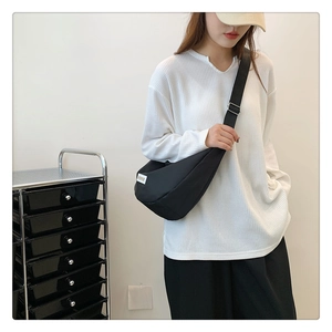 Gros plan du sac bandoulière demi-lune noir avec étiquette tissée et sangle réglable