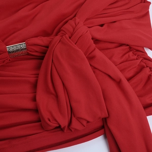 Detailed close-up of red knit fabric with elegant ruching and a golden metal buckle