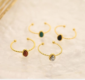 Close-up of golden oval gemstone rings with twisted bands in four varied colors