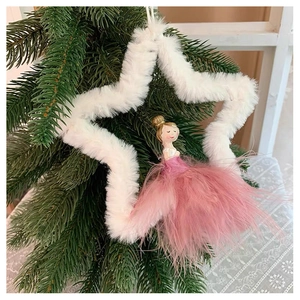Detail of plush Christmas angel ornament with pink feathers hanging on a pine branch