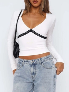 Détail du crop top blanc à manches longues avec bordure en dentelle noire au décolleté