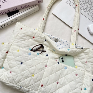 Quilted white tote bag detail with colorful heart embroidery and spacious inner compartment