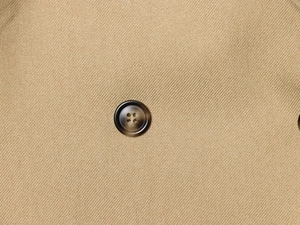 Detailed close-up of khaki blazer featuring brown four-hole resin buttons and twill fabric