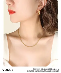 Close-up of polished 18K gold plated titanium steel hoop earrings worn by a model