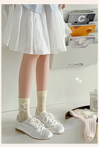 Close-up detail of cream crew socks with mesh knit pattern and white silk bow accent