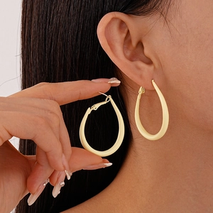 Close-up of a large teardrop-shaped earring in matte cream yellow on a model's ear