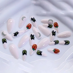 Halloween almond press-on nails featuring cute black cat, pumpkin, and moon designs