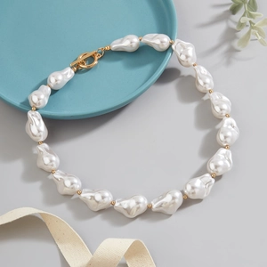 Baroque irregular pearl necklace with gold T-bar clasp shown on an elegant aesthetic tray
