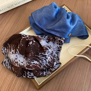 Elegant silk hair scrunchies in navy blue and marbled brown on a luxury wooden tray