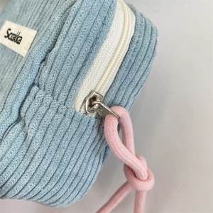 Detailed view of sky blue corduroy makeup bag with pink knot zipper puller