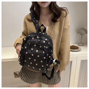 Detail of a black floral backpack with adjustable straps and smooth zipper closure