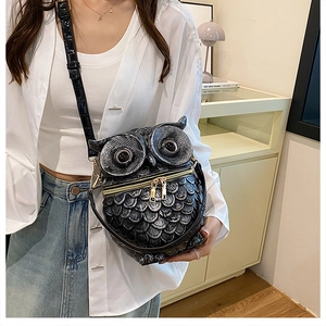 Close-up of owl-shaped crossbody bag featuring textured feather patterns and gold zippers