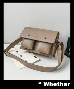 Detail of khaki leather messenger bag featuring double front pockets and embossed texture