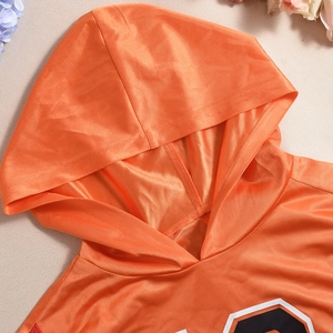 Vue détaillée du haut de sport orange à capuche montrant la texture du tissu mesh respirant