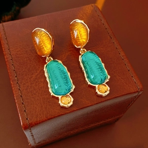 Detail view of vintage amber and peacock green gemstones set in gold metal earrings