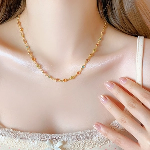 Nahaufnahme der goldenen Kette mit bunten eingelegten runden Edelsteinen am Hals