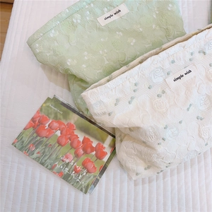 Detail of mint green floral jacquard fabric and simple wish label on a makeup bag