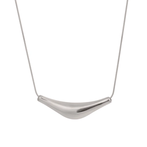 Détail macro du pendentif géométrique argenté et de la fine chaîne en acier inoxydable