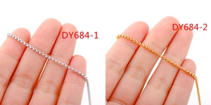 Detail of 18k gold and silver box chains showing smooth texture and high polish finish