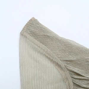 Macro shot of pleated champagne gold fabric with metallic texture on long sleeve dress