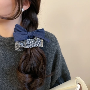 Detail of dark blue denim bow scrunchie with black and white grid pattern on hair