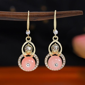Macro shot of traditional style gold earrings with pink beads and sparkling crystal accents