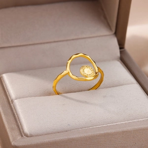 Close-up of golden geometric ring with hammered texture and beaded disc in jewelry box