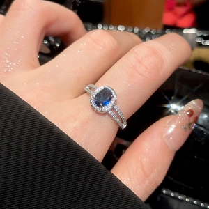 Macro view of blue oval gemstone ring with pavé cubic zirconia on silver band